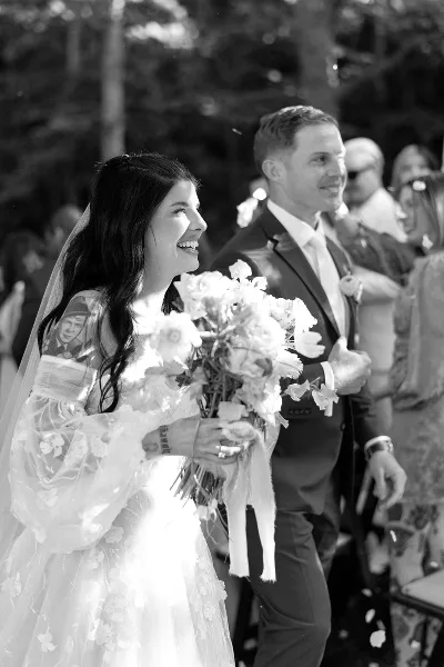 A black and white photograph of a bride and groom smiling during a wedding ceremony.