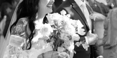A black and white photograph of a bride and groom smiling during a wedding ceremony.