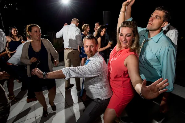 Wedding guests dancing at a reception under bright lights
