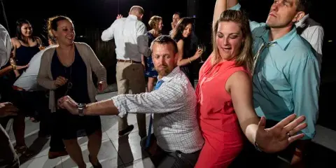 Wedding guests dancing at a reception under bright lights