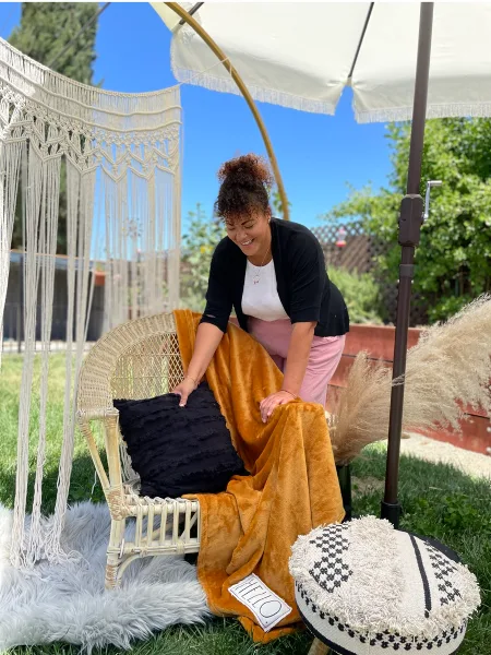 Shayna Holt arranging event decor on a wicker chair outdoors