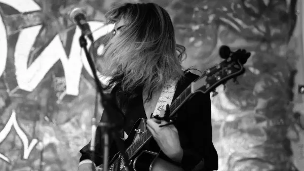 A musician playing an electric guitar at a microphone during a live performance.