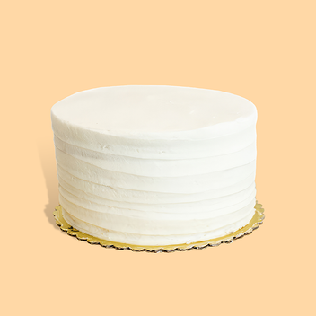 A white, multi-tiered wedding cake with smooth frosting on a gold cake board.