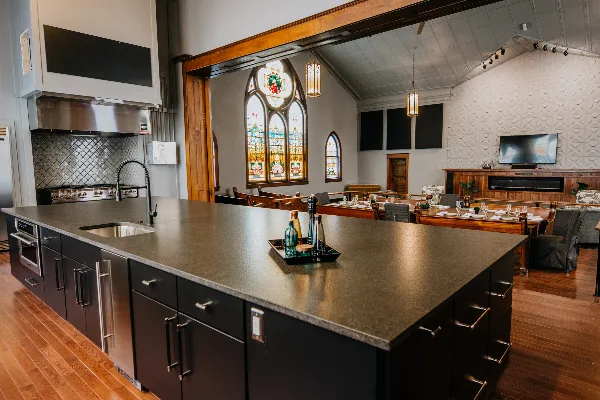 Interior view of a renovated church venue featuring a modern kitchen island, stained glass windows, and a dining area.