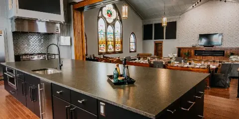 Interior view of a renovated church venue featuring a modern kitchen island, stained glass windows, and a dining area.
