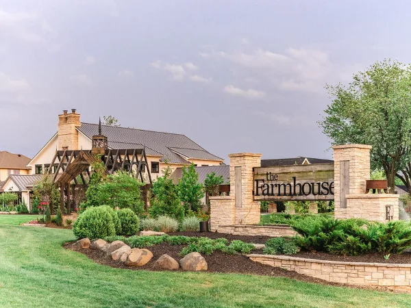 Exterior view of The Farmhouse wedding venue featuring the main building, wooden arbor, and entrance signage.