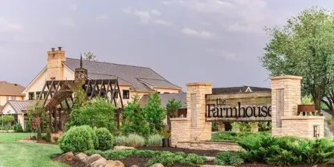 Exterior view of The Farmhouse wedding venue featuring the main building, wooden arbor, and entrance signage.
