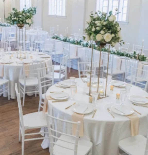 Elegant wedding reception with round tables, white chairs, and floral centerpieces