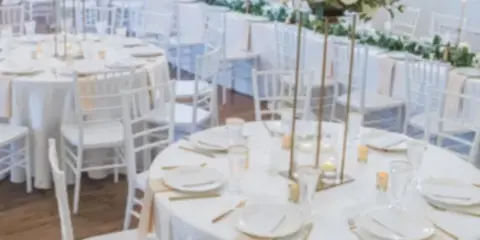 Elegant wedding reception with round tables, white chairs, and floral centerpieces