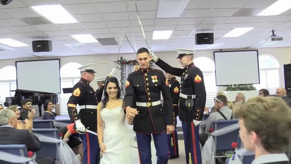 A bride and groom in military dress uniforms walk down the aisle during a wedding ceremony.