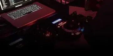 A professional DJ setup featuring a laptop and Pioneer DJ controller on a table.