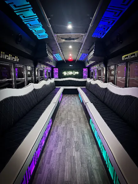Interior of a party bus with black and white leather seating, LED lighting, and a 'Top Notch Limos' sign on the back wall.