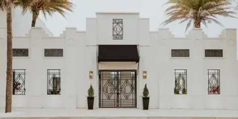 Exterior view of The Clay Theatre building featuring a white facade, Art Deco architectural details, and a central entrance.