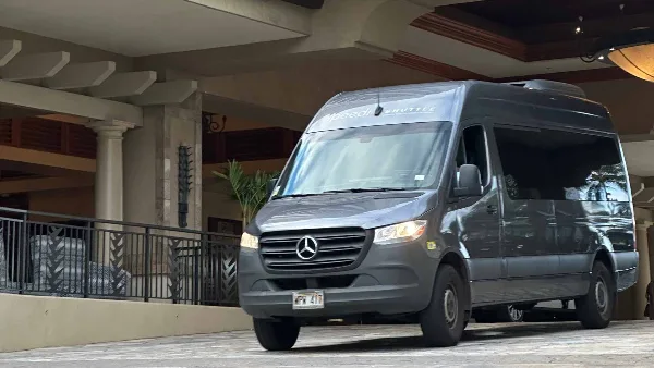 A gray Mercedes-Benz Sprinter shuttle van with SpeediShuttle branding parked at a hotel entrance.