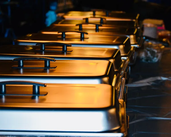 A row of stainless steel chafing dishes lined up on a table.
