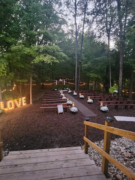Outdoor wedding ceremony setup with wooden benches and floral arrangements in a forest clearing