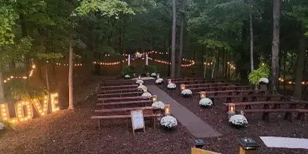 Outdoor wedding ceremony setup with wooden benches and floral arrangements in a forest clearing