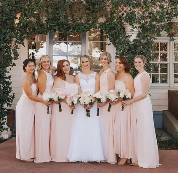 A bride and her bridesmaids posing together with styled hair and makeup.