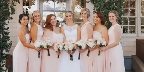 A bride and her bridesmaids posing together with styled hair and makeup.