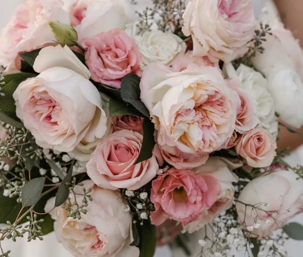 Close-up of a floral arrangement with pink and white roses and greenery.