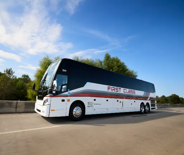 White First Class Transportation full-size motorcoach driving on a highway under a blue sky