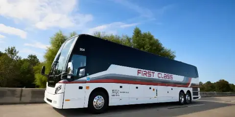 White First Class Transportation full-size motorcoach driving on a highway under a blue sky