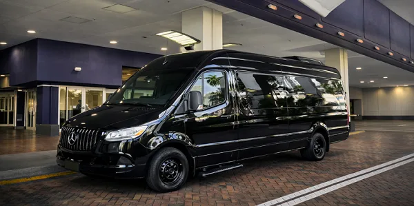 A black Mercedes-Benz Sprinter van parked at a covered drop-off area.