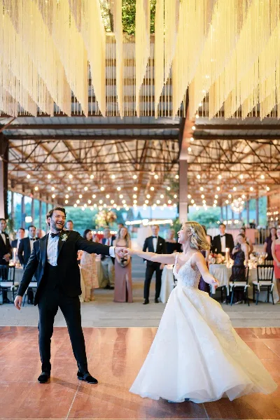 A bride and groom dancing together at a wedding reception under a decorative ceiling installation.