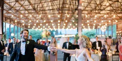 A bride and groom dancing together at a wedding reception under a decorative ceiling installation.