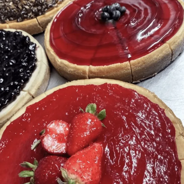 Close-up of a baked fruit tart topped with fresh strawberries and a glossy red glaze.