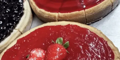 Close-up of a baked fruit tart topped with fresh strawberries and a glossy red glaze.