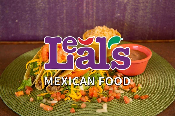 A plate of tacos with shredded cheese, lettuce, and tomatoes, served with a side of rice and beans.