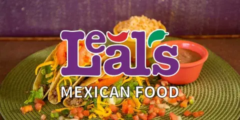 A plate of tacos with shredded cheese, lettuce, and tomatoes, served with a side of rice and beans.