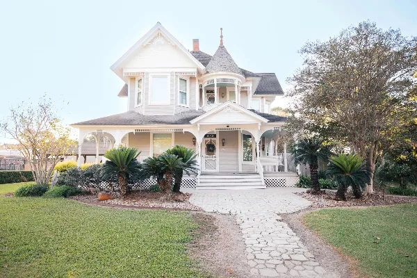 Exterior view of a white Victorian-style wedding venue with a stone pathway and landscaped garden.