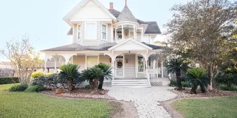 Exterior view of a white Victorian-style wedding venue with a stone pathway and landscaped garden.