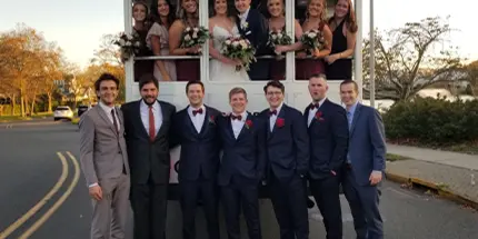 A wedding party posing in front of a white wedding trolley.