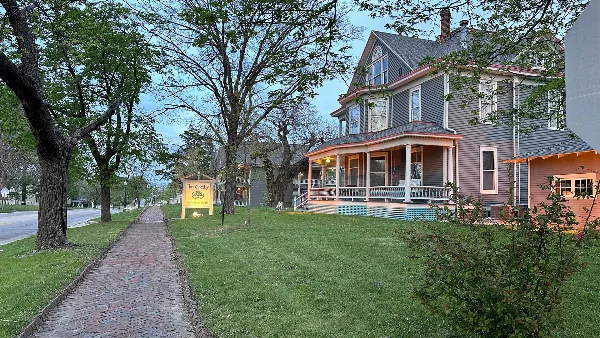 Exterior view of The Shelby Inn, a historic boutique hotel with a Victorian-style porch and a brick walkway.