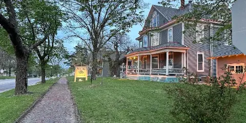 Exterior view of The Shelby Inn, a historic boutique hotel with a Victorian-style porch and a brick walkway.