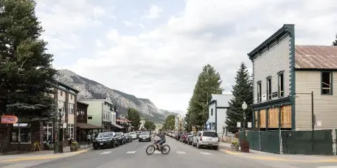 Street scene in Crested Butte with parked cars, storefronts, and a mountain in the background.