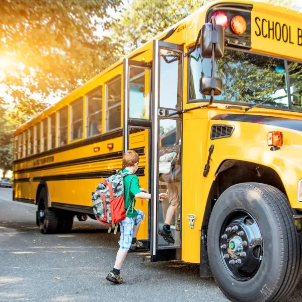 A yellow school bus with a child boarding the vehicle.