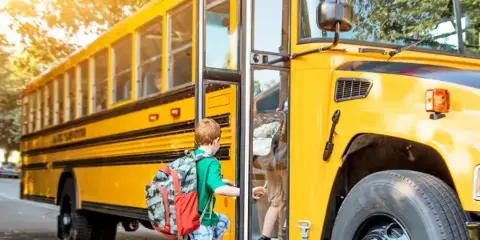A yellow school bus with a child boarding the vehicle.