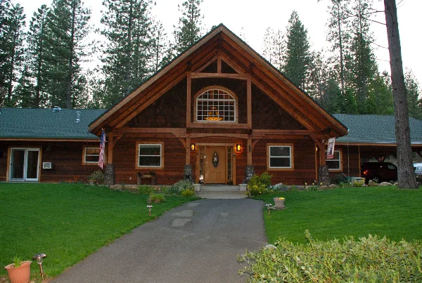 Exterior view of a large timber-frame inn with a manicured lawn and paved walkway leading to the entrance.