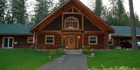 Exterior view of a large timber-frame inn with a manicured lawn and paved walkway leading to the entrance.