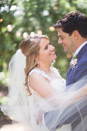 A bride and groom looking at each other affectionately in an outdoor setting.