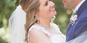 A bride and groom looking at each other affectionately in an outdoor setting.