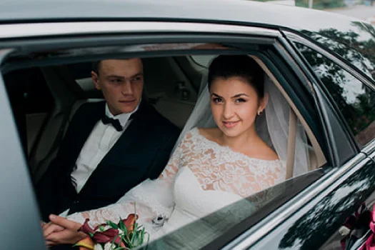 Bride and groom seated inside a luxury sedan during a wedding event