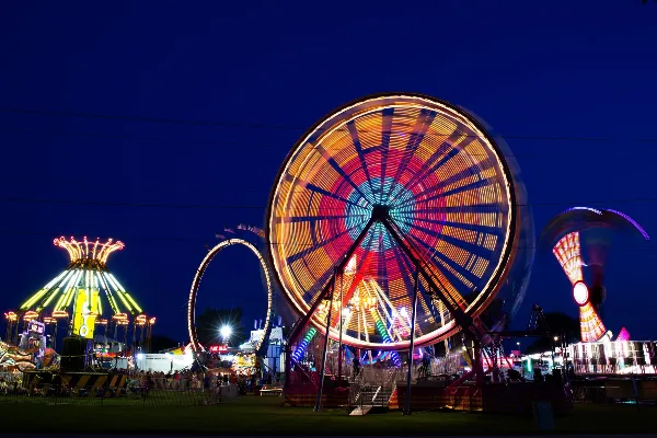 Illuminated carnival rides and midway at night at the fairgrounds.