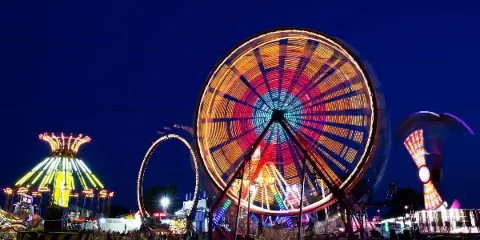Illuminated carnival rides and midway at night at the fairgrounds.