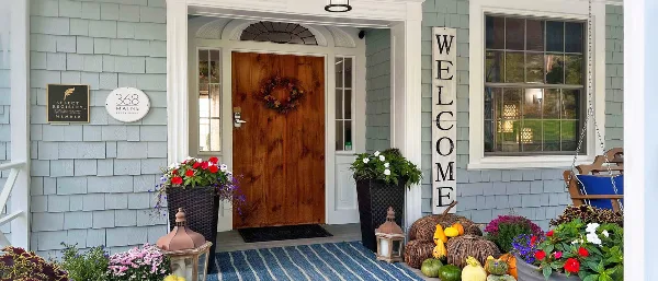 Front entrance of a lodge with a wooden door, '368 Maine Restaurant' sign, and fall decorations.