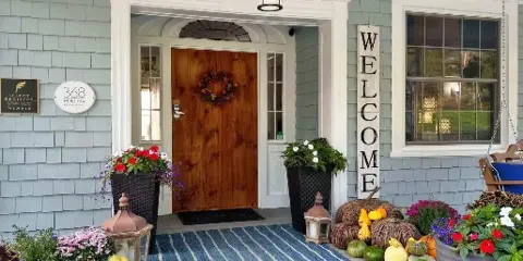 Front entrance of a lodge with a wooden door, '368 Maine Restaurant' sign, and fall decorations.